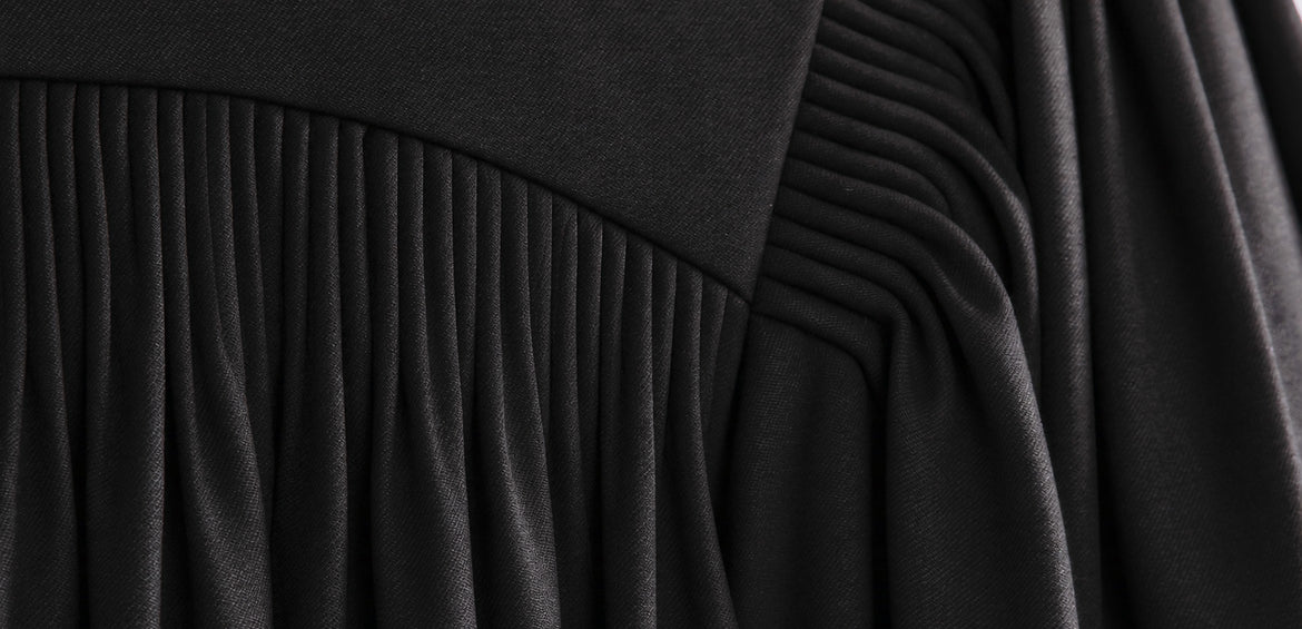 Pleated yoke of a black clergy robe with a light, flowing drape