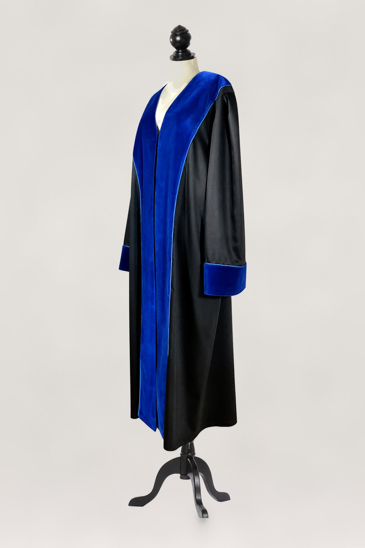 Black UPC First Instance judicial robe with blue velvet facings on lapels and cuffs, finished with blue piping, side view on a tailor dummy