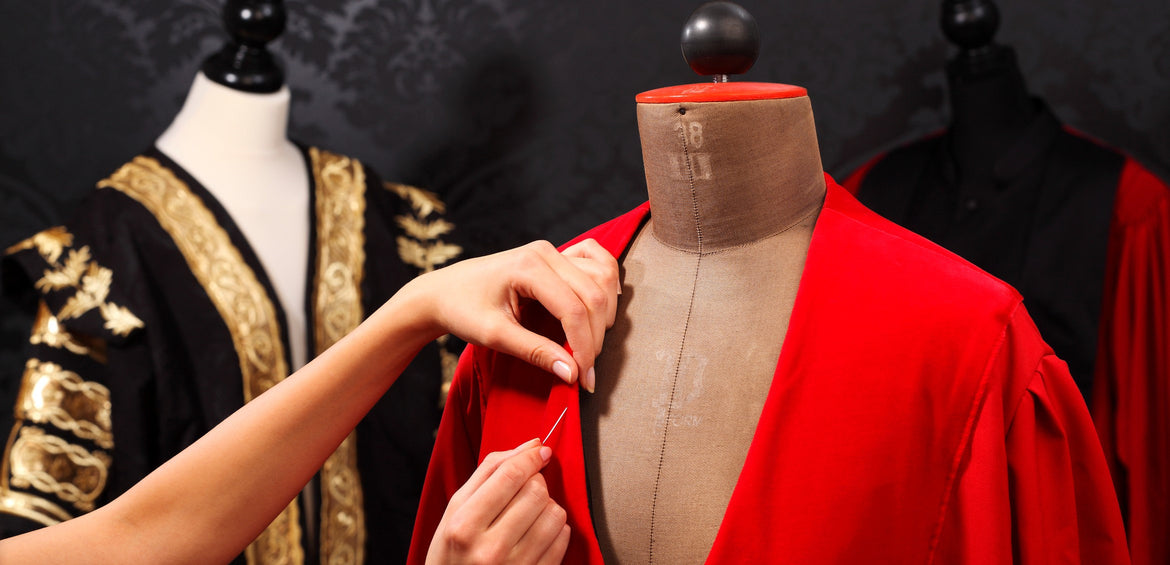 A red robe being pinned on a dress form in the atelier
